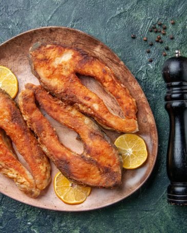 top-view-delicious-fried-fishes-lemon-slices-brown-plate-spices-mix-colors-table-with-free-space